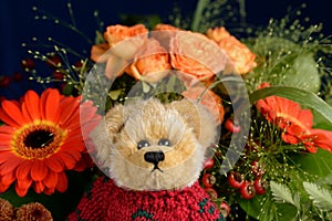 Teddy bear in front of a flower bouquet Orange flowers