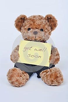 Teddy bear holding a yellow sign saying Get Well Soon isolated on white background photo