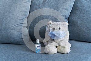 Teddy bear in mask and glasses with hand sanitizer