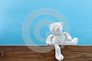 Teddy bear on old wood in front blue wall background.