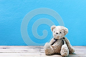 Teddy bear on old wood in front blue wall background.