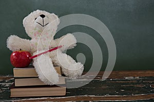 Teddy bear, pencil and apple on stack of books