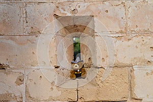 Teddy bear perched on an arrowslit castle window