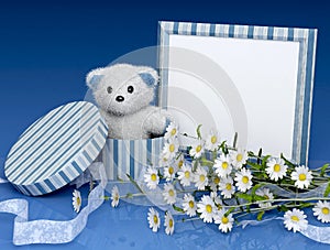 Teddy bear with a photo frame and flowers