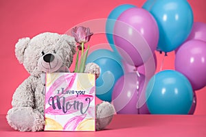 teddy bear with pink tulip and postcard with text I Love You Mom, mothers