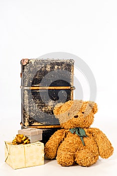 Teddy bear, presents and old suitcase on white background