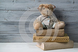 Teddy bear in reading glasses sitting on the stack of old books