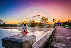 Teddy Bear with red heart sitting near the beach