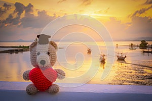 Teddy Bear with red heart sitting near the beach