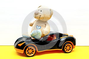 Teddy bear with sedan car toy for children play on white yellow background, baby's childhood development