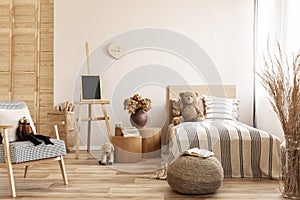 Teddy bear on single wooden bed in natural kid`s bedroom