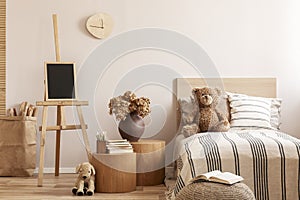 Teddy bear on single wooden bed in natural kid`s bedroom photo