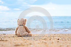 Teddy bear sit alone at the seashore