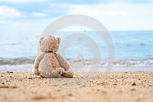 Teddy bear sit alone at the seashore