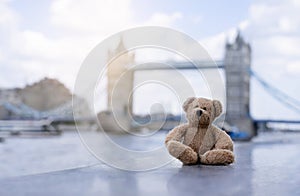 Teddy bear sitting alone with blurry london tower bridge background, The forgotten bear sitting by the river, lost property, Lonel