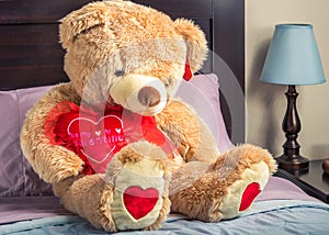 A teddy bear sitting on a bed with a heart that says `Be my valentine