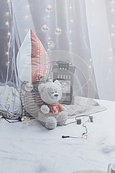Teddy bear sitting on the bed with pillows and decorative flashlight. Nobody. Romantic bedroom decor.