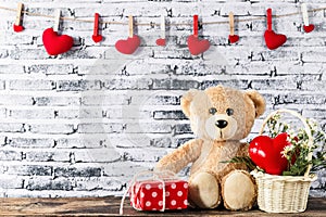 Teddy bear sitting with gift box and red heart shaped
