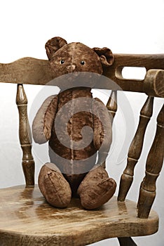 teddy bear sitting in an old vintage wooden armchair