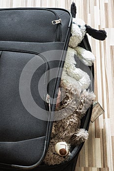 Teddy bear and soft toys sticking out of a full suitcase