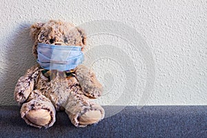 Teddy bear with a surgical mask in home