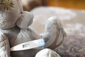 Teddy bear with temperature. bear in bed with thermometer