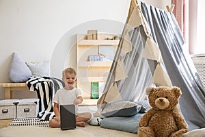 Teddy bear and tent in a playroom interior where a young boy is playing