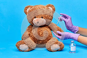 teddy bear toy and hands with vaccine and syringe