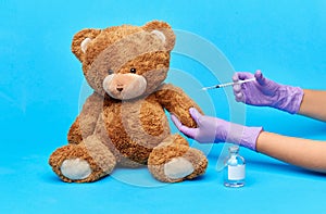 teddy bear toy and hands with vaccine and syringe