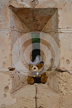 Teddy bear toy perched on an arrowslit or loophole castle window