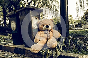 The teddy-bear was throw away sitting beyside the garbage trash