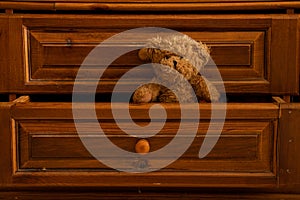 Teddy brown bear sits in a wooden pull-out old drawer in the bedroom as a background,furniture