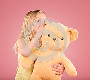 Teddy, secret and young girl talking and whispering to a toy bear in a studio. Playing, child and bonding with love and