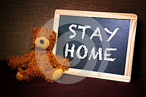 Teddybear with chalkboard and the words Stay Home