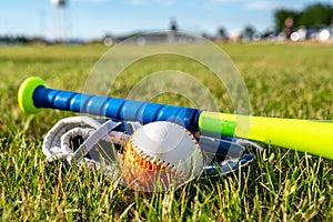 Tee ball  glove  and bat on green grass. Equipment commonly used in youth sports