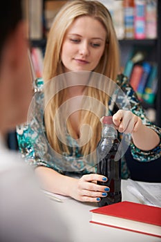 Teeange Female Student With Bottle Of Fizzy Drink In Class