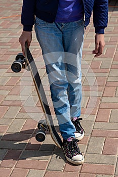 Teen age Girl in black sneakers on a skateboard. Feet on a skateboard