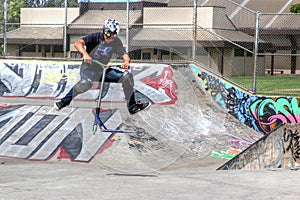 Teen-aged boy practicing on scooter at skate-park