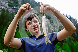 Teen ager fisherman shows happy, catching an Salvelinus alpinus photo