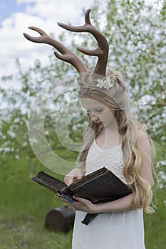 Teen beautiful blonde girl wearing white dress with deer horns o