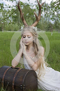 Teen beautiful blonde girl wearing white dress with deer horns o