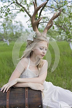 Teen blonde girl wearing white dress with deer horns on her head