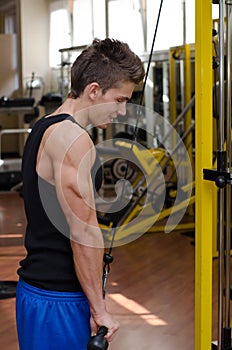 Teen bodybuilder exercising triceps with gym equipment