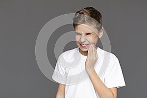 Teen boy with acute toothache, grey background