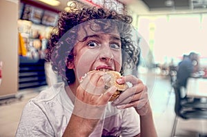 Teen boy bites his burger