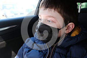 A teen boy in car wearing surgical medical black face mask as a protection against virus disease