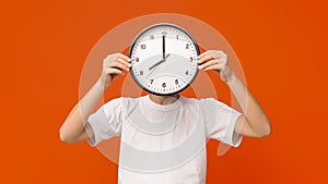 Teen boy covering his face with big clock, orange panorama