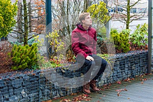 Teen boy dreaming about future ideas, visions and plans expecting good future sitting outdoor in city park