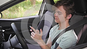 Teen boy on driver seat scrolling smartphone in car