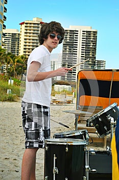 Teen boy with drums on the beach